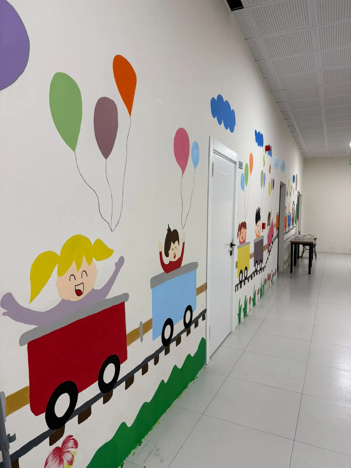 Duvarlarında balon ve tren çizimleri olan, resimli kitap sayfasını andıran Sincan koridoru